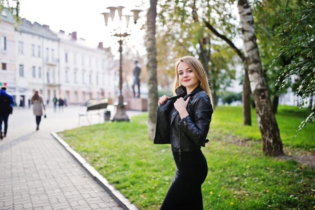 Elegant blonde girl wear on black leather jacket posing at streets of town.