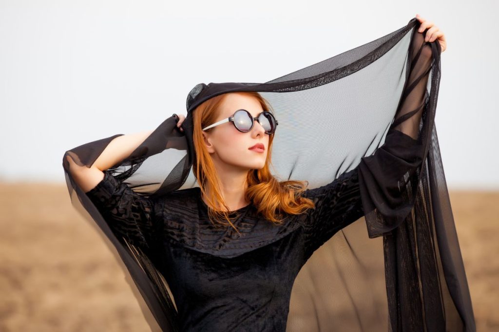 photo of beautiful young woman holding shawl on the wonderful field and sky background