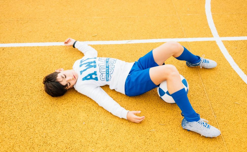 Soccer player boy lying on the court