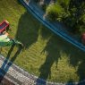 Garden worker is using a fertilizing distributor to feed the grass aerial view.