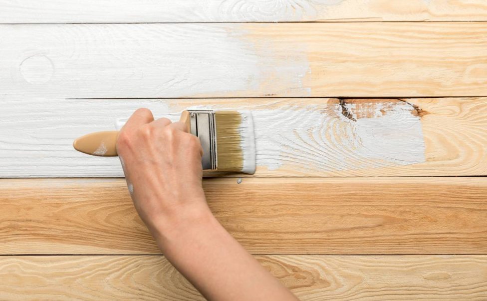 cropped view of woman painting wooden surface in white