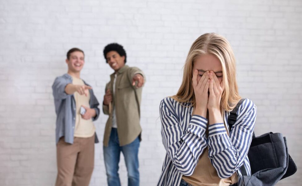 European and african american teens zoomers guys laugh at crying female with backpack in school or college